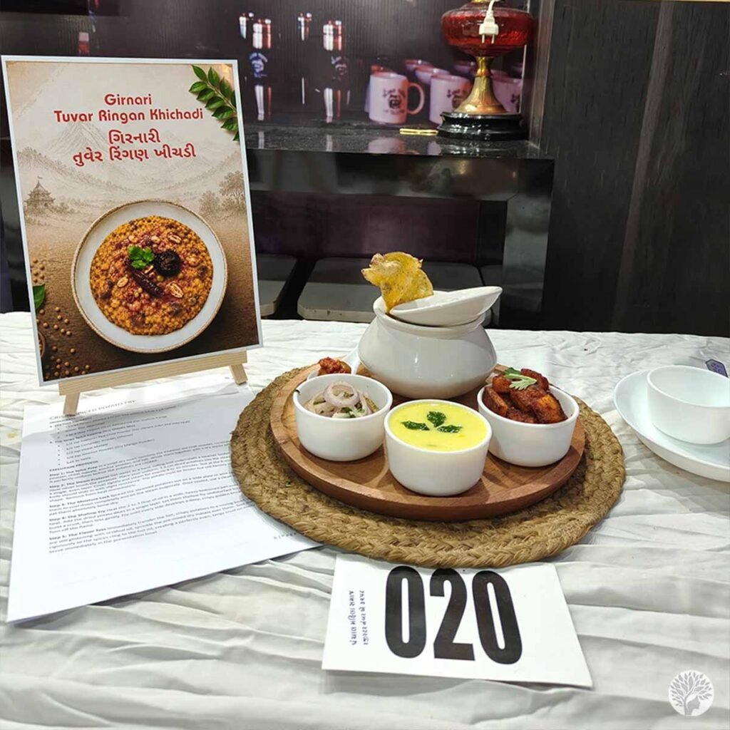 A beautifully arranged culinary competition table display featuring an easel with a menu sign next to a round wooden platter of traditional Indian food entries.