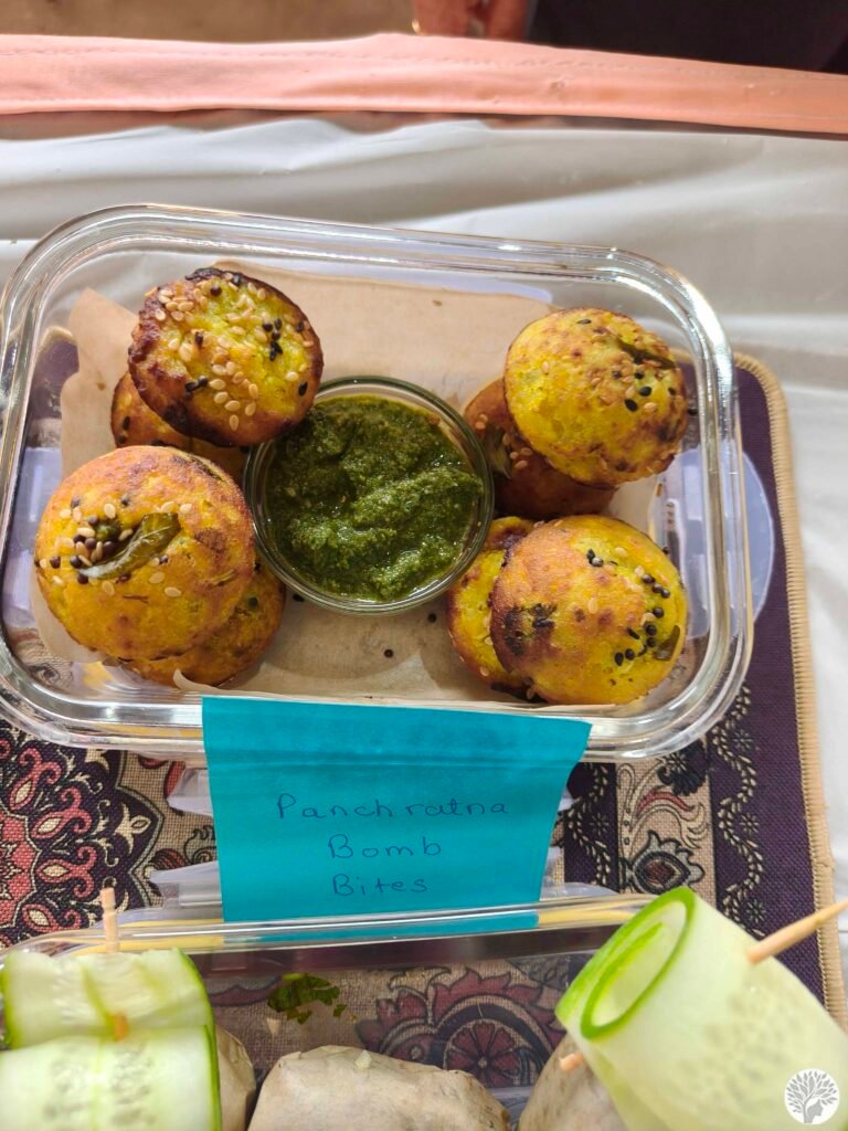 A close-up of Panchratna Bomb Bites—crispy ragi, quinoa, and wheat flour bites with a surprise savory center, garnished with fresh cucumber slices.
