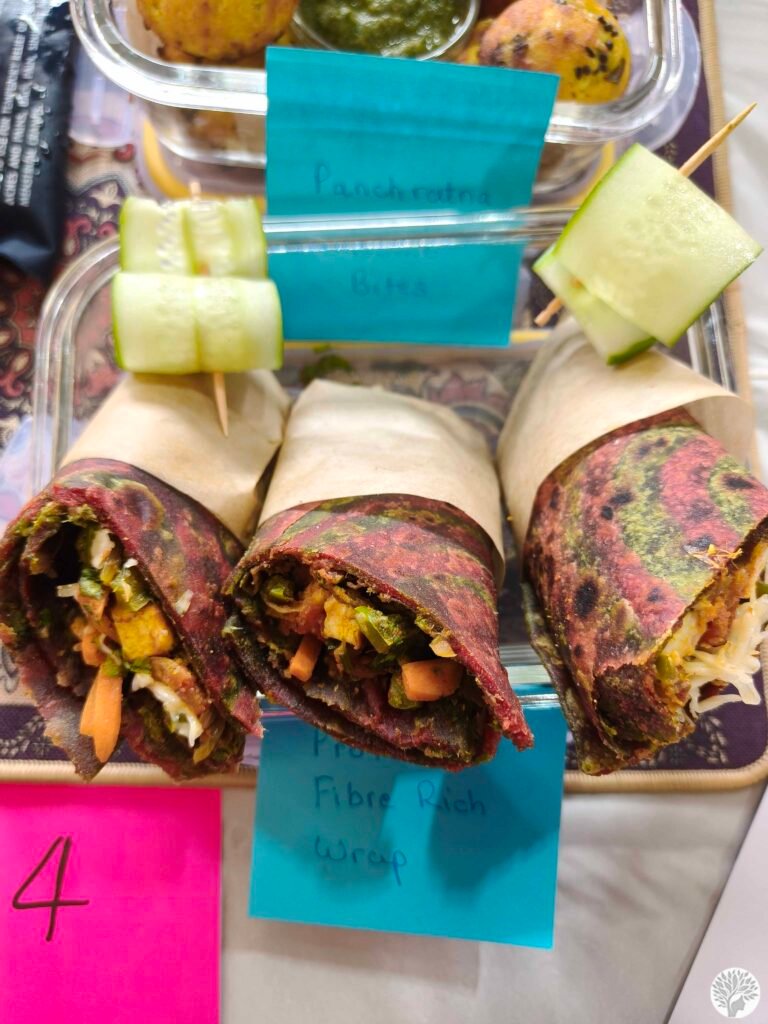 A close-up of the Protein Fibre Rich Wrap made from beetroot and sprouted flatbread, tightly packed with fresh vegetables, pumpkin seeds, and a creamy spread.