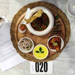 Overhead top-down view of a traditional Kathiyawadi platter with Girnari Tuvar Ringan Khichadi, yellow yogurt kadhi soup, and crispy potato fry on a wooden tray.